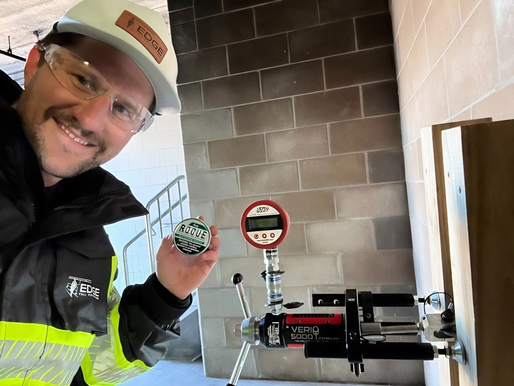 Michael McCarty of EDGE Fall Protection performing an anchor pull test on a concrete wall anchor with a hydraulic load tester and digital gauge